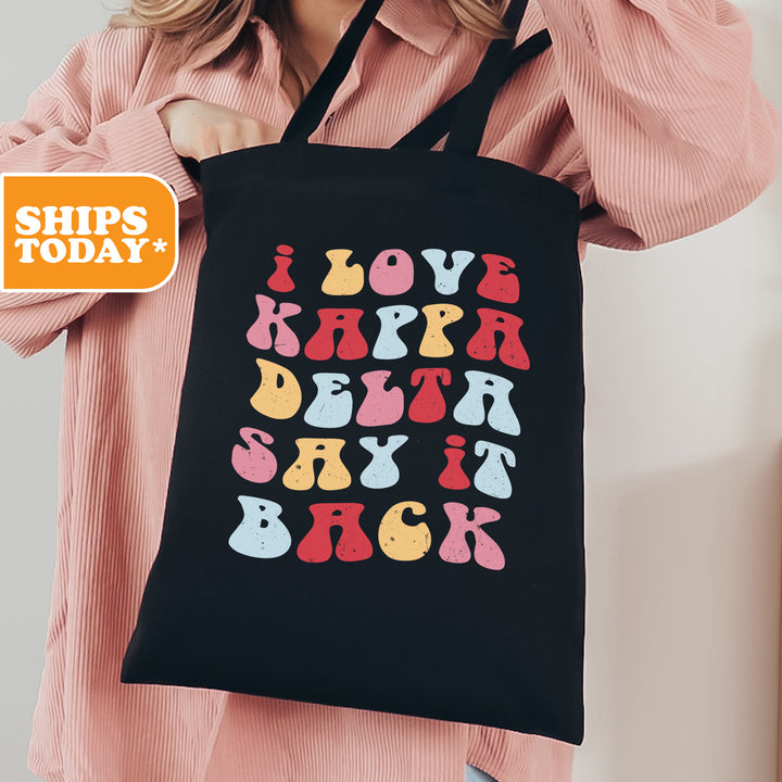 a woman holding a black shopping bag with colorful letters