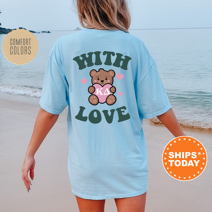 a woman walking on the beach with a teddy bear on her shirt