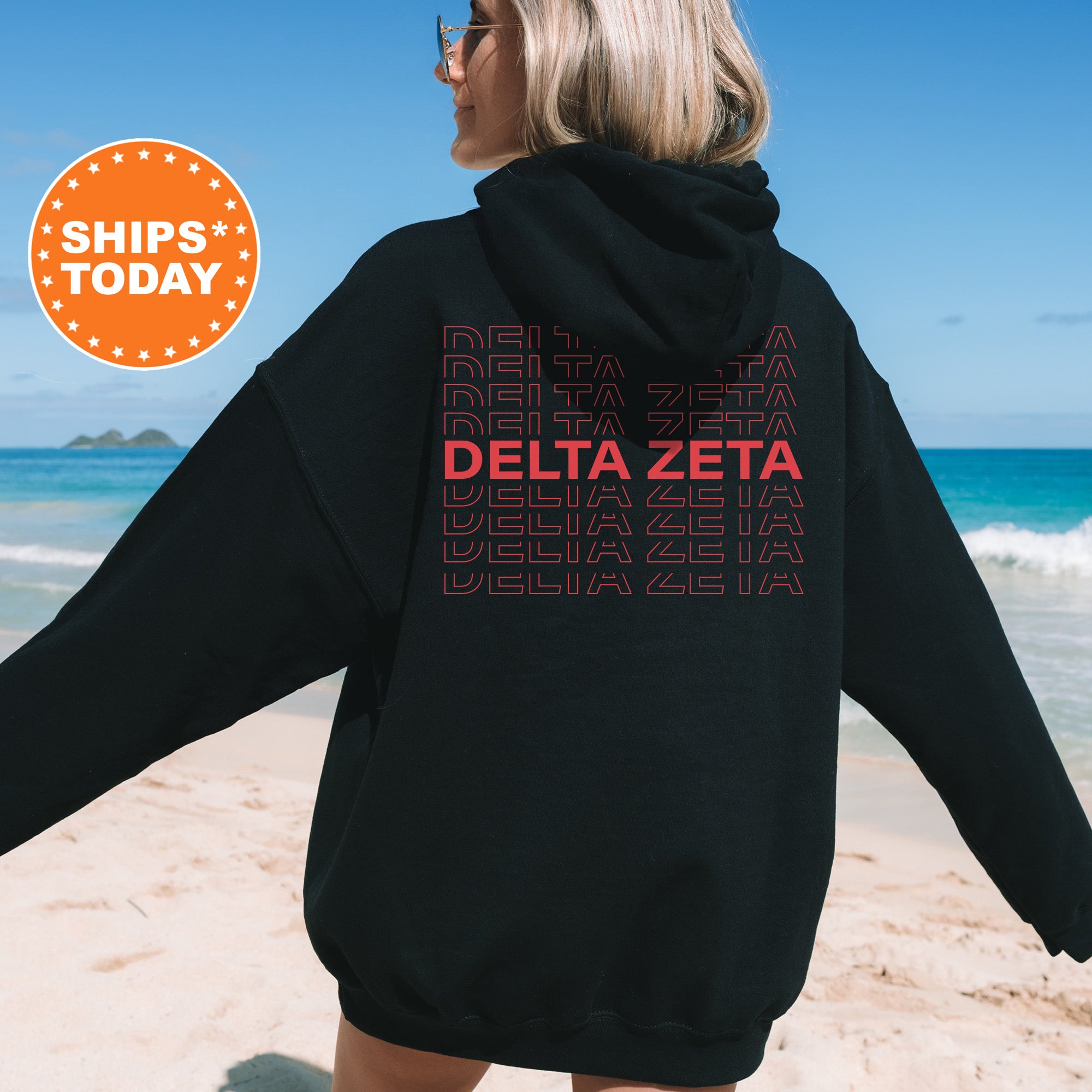 a woman wearing a black delta zeta hoodie on the beach