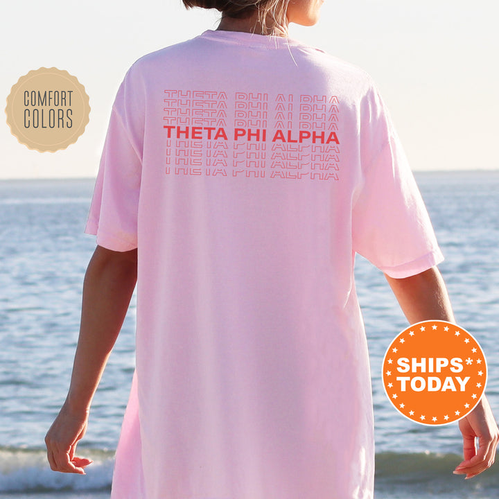 a woman wearing a pink shirt that says thea phi alpha