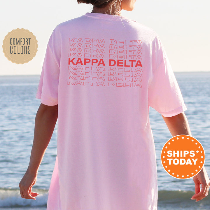 a woman standing on a beach wearing a pink kapa delta shirt