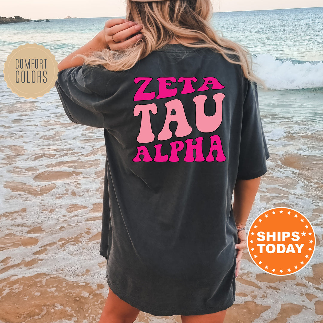 a woman standing on a beach wearing a t - shirt that says zeta tau