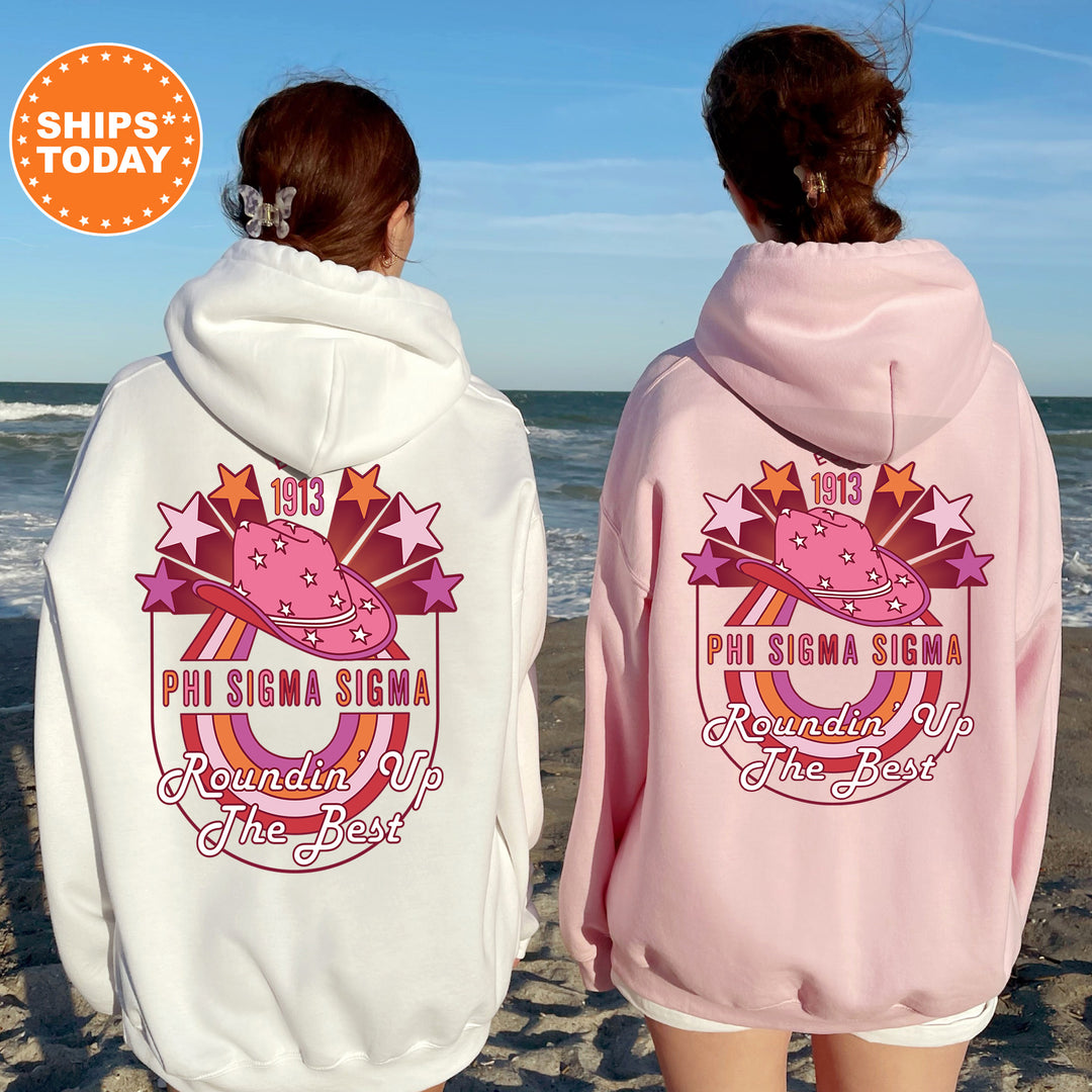 two women wearing pink and white sweatshirts on the beach