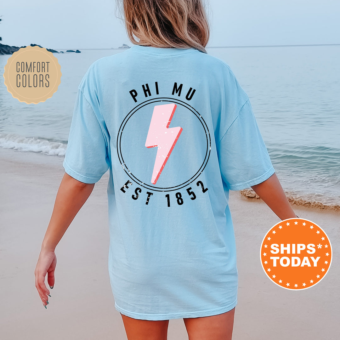 a woman walking on the beach wearing a blue shirt with a lightning bolt on it