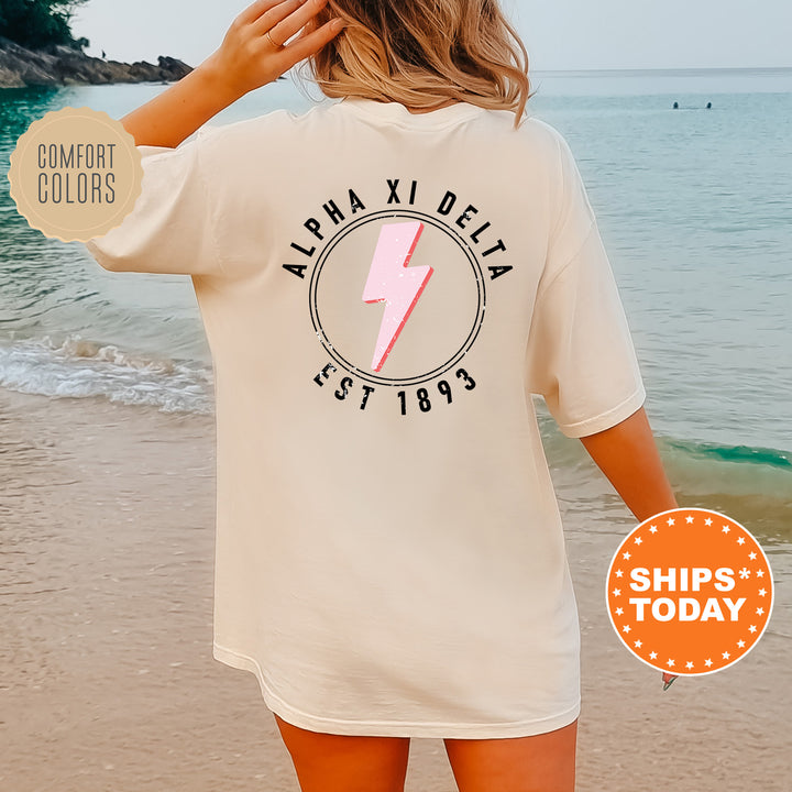 a woman standing on a beach wearing a shirt with a lightning bolt on it