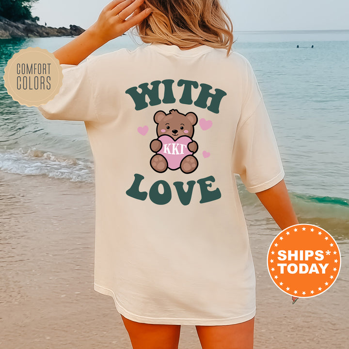 a woman standing on a beach wearing a t - shirt with a teddy bear on