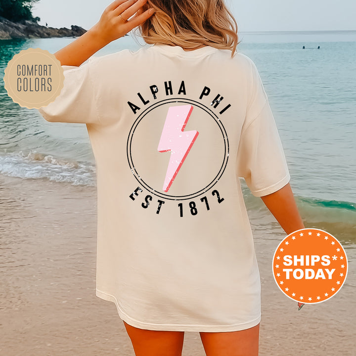 a woman standing on a beach wearing a shirt with a lightning bolt on it