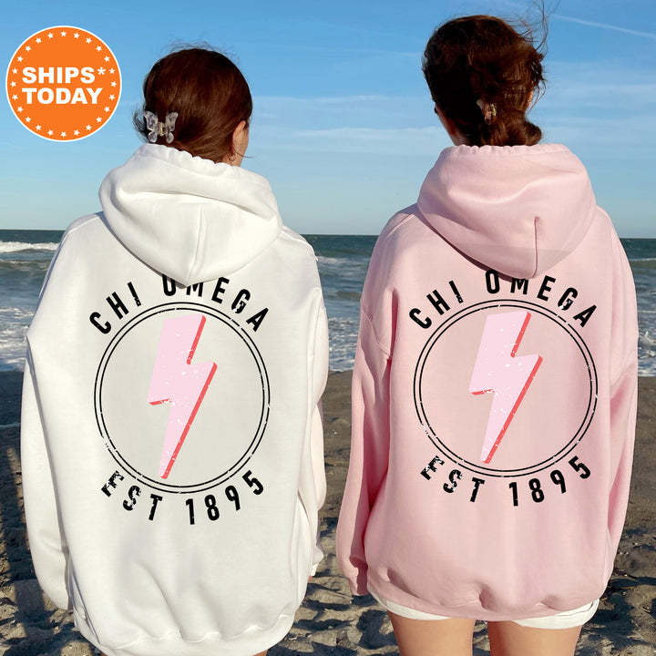 two women wearing pink and white sweatshirts on the beach