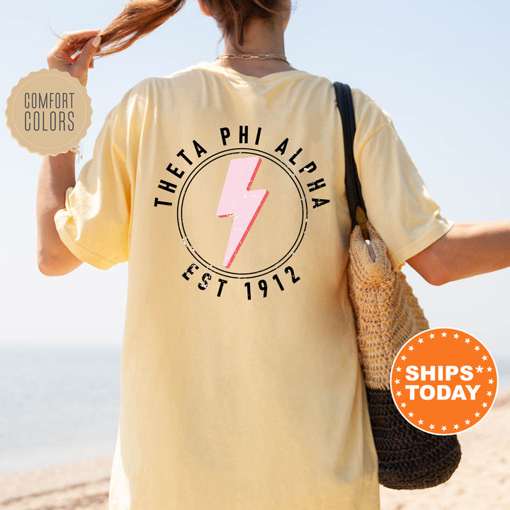 the back of a woman's yellow shirt with a pink lightning bolt on it