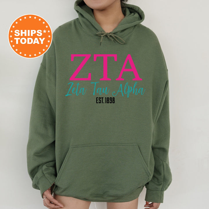 a woman wearing a green hoodie with a pink zita on it