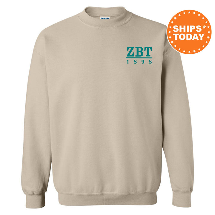 a beige sweatshirt with a green and blue zbtt logo