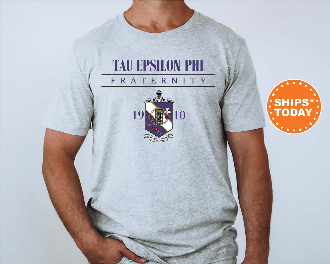 a man wearing a gray t - shirt with the words tau epsion phi fraternity