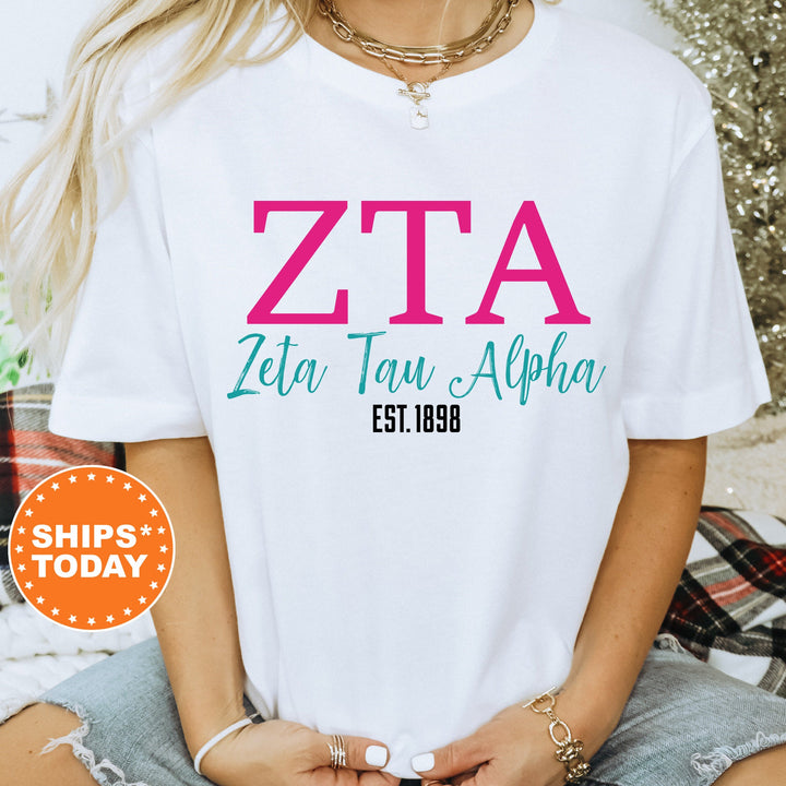 a woman wearing a white tshirt with a pink zta on it