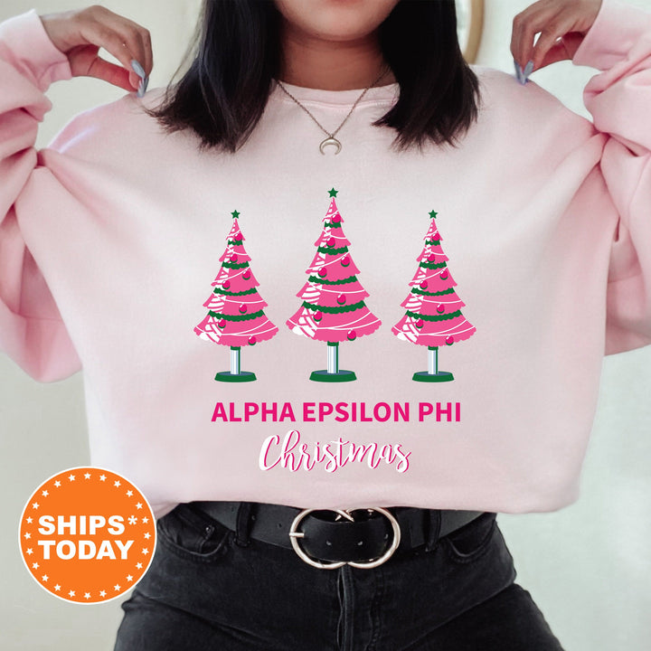 a woman holding up a pink sweatshirt with christmas trees on it