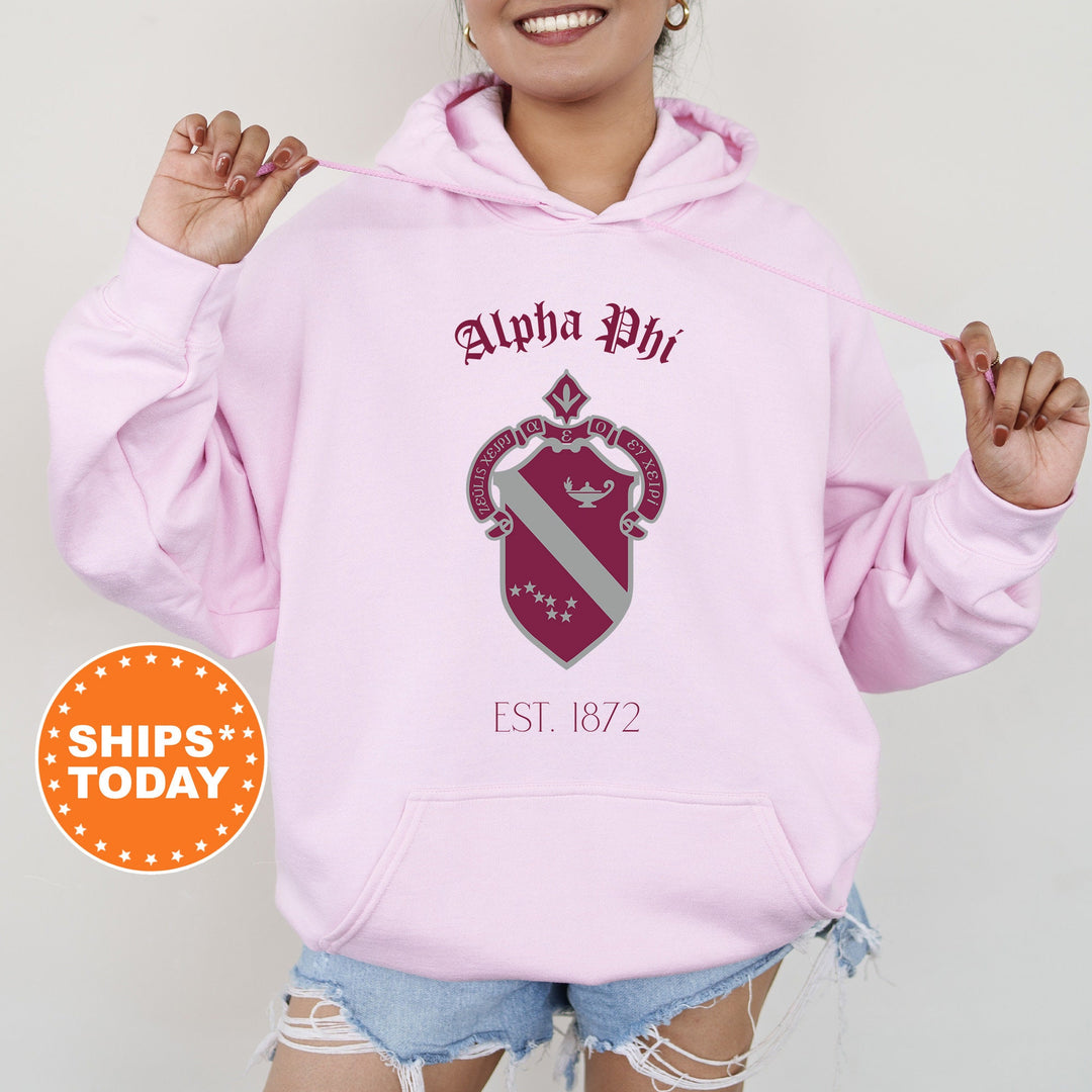 a woman wearing a pink hoodie with a crest on it