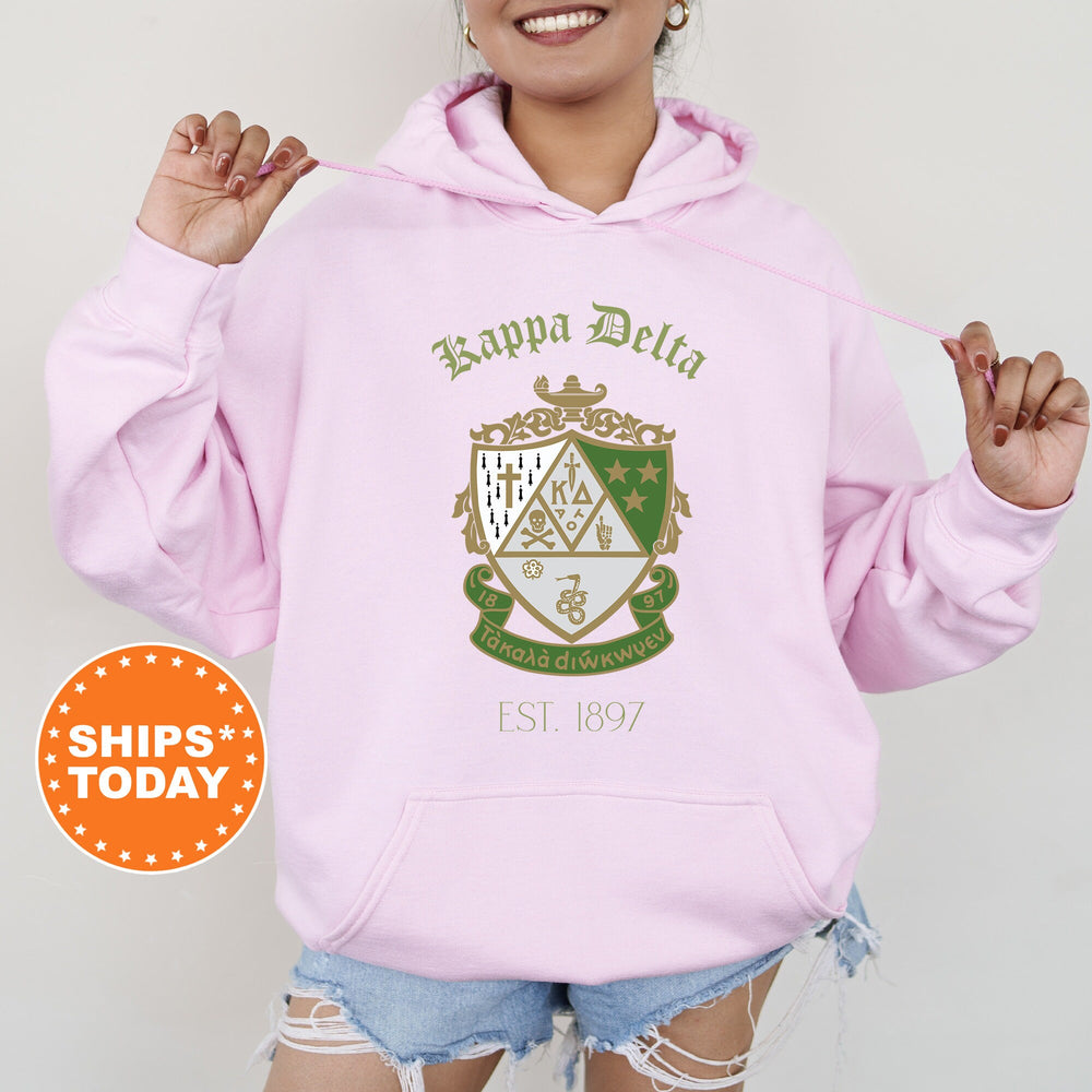 a woman wearing a pink hoodie with a crest on it