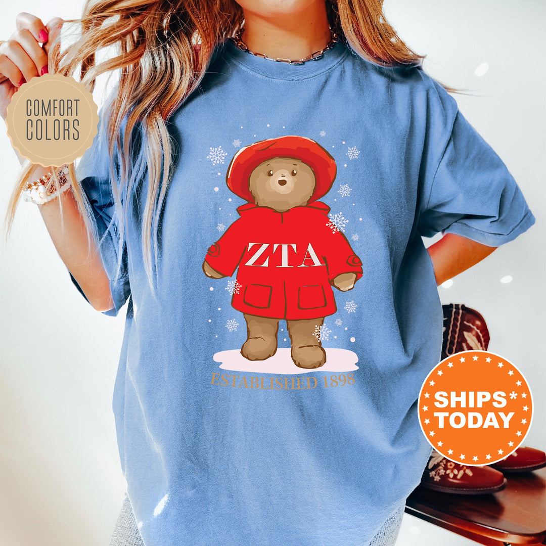 a woman wearing a blue shirt with a picture of a teddy bear wearing a red