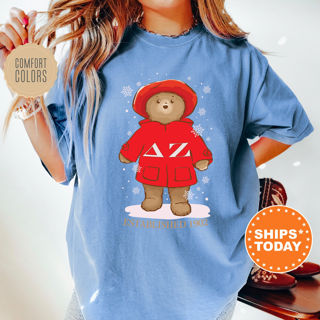 a woman wearing a blue shirt with a picture of a teddy bear wearing a red