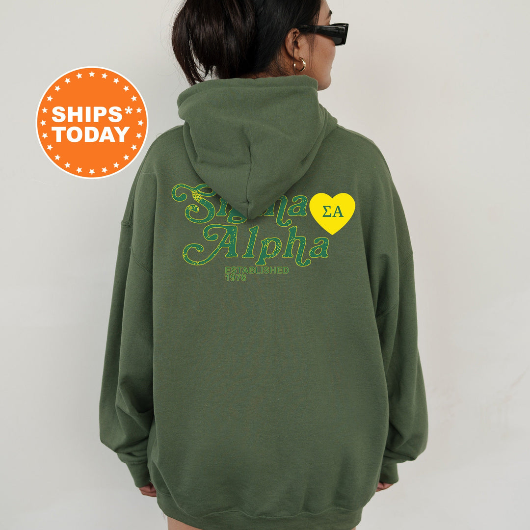 a woman wearing a green hoodie with a yellow heart