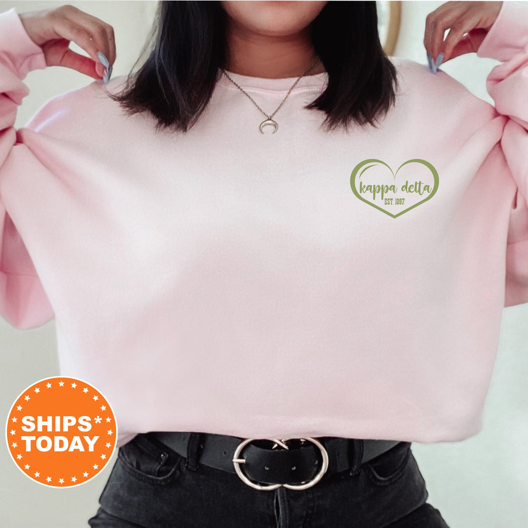 a woman wearing a pink sweatshirt with a green heart on it