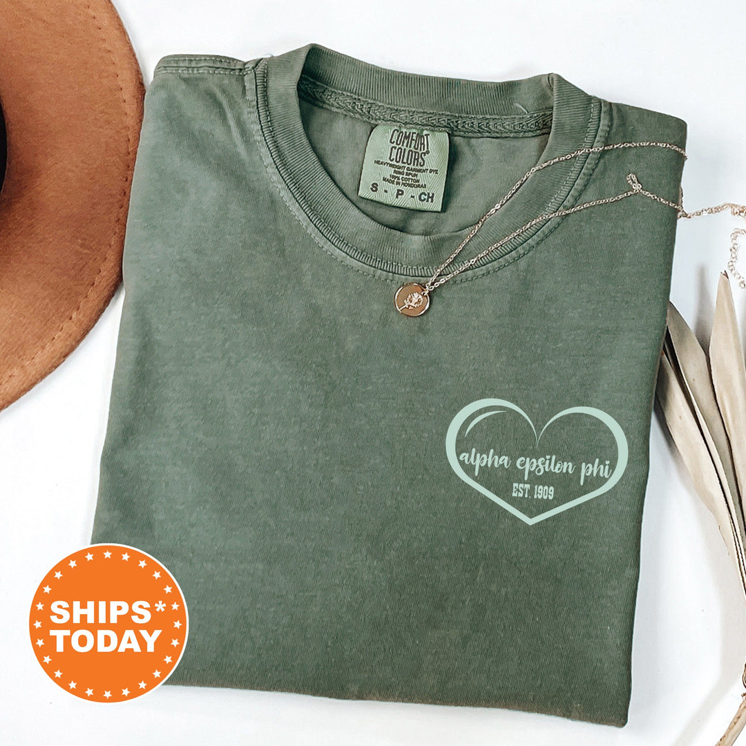 a green shirt with a heart on it and a hat next to it