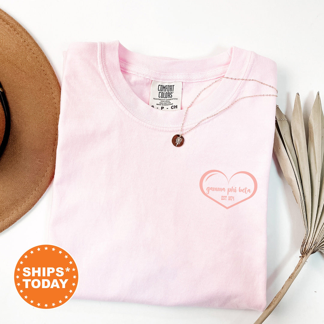 a pink shirt with a heart on it and a hat next to it