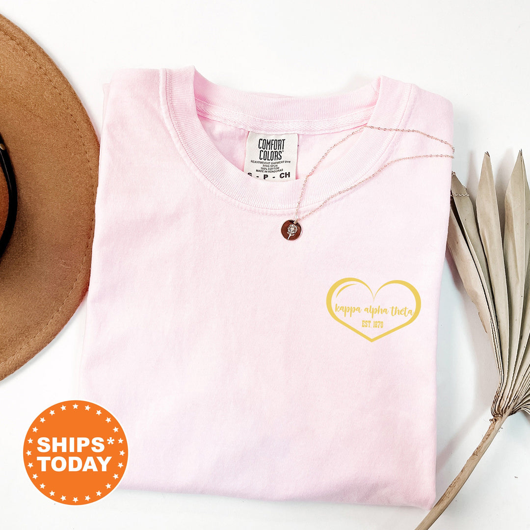a pink shirt with a heart on it and a hat next to it