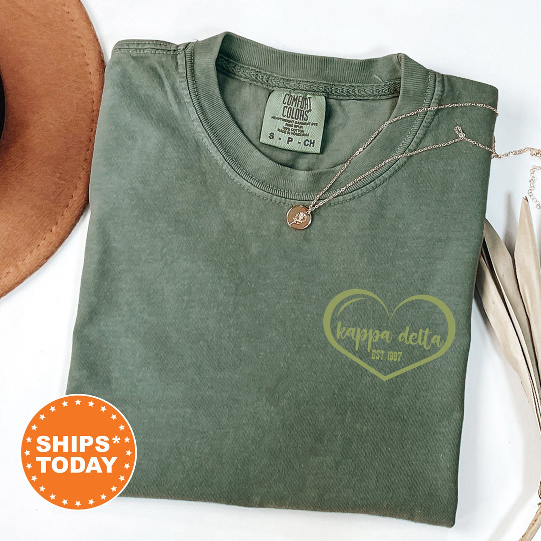 a green t - shirt with a heart on it and a hat next to it