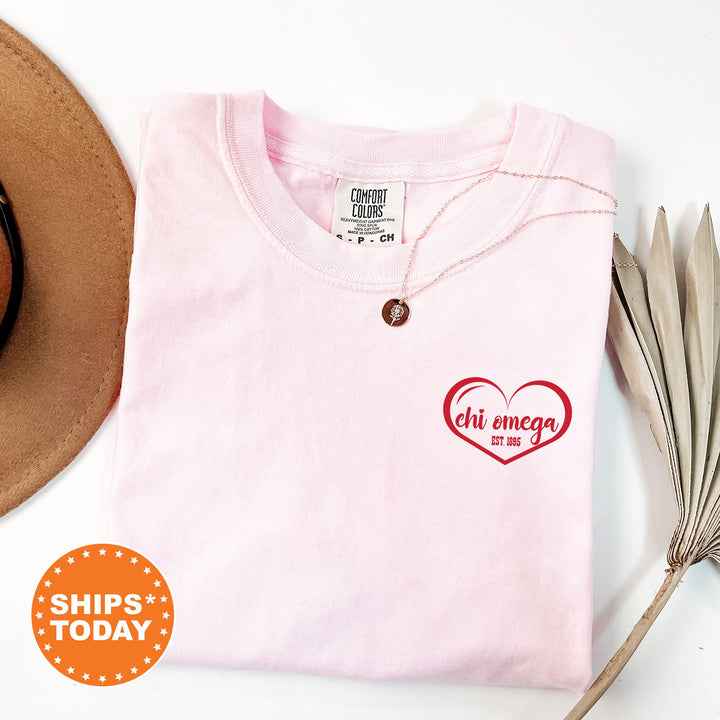 a pink shirt with a heart on it and a hat next to it