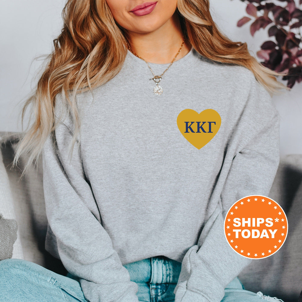 a woman sitting on a couch wearing a grey sweatshirt with a yellow heart on it