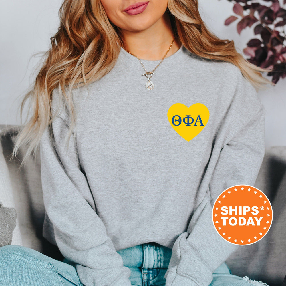 a woman wearing a grey sweatshirt with a yellow heart on it