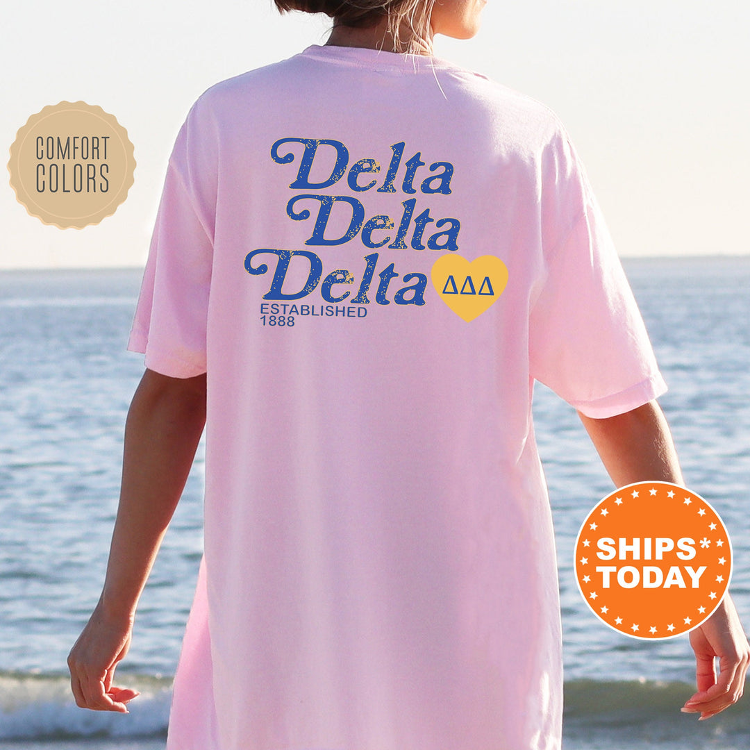 a woman wearing a pink delta delta shirt on the beach