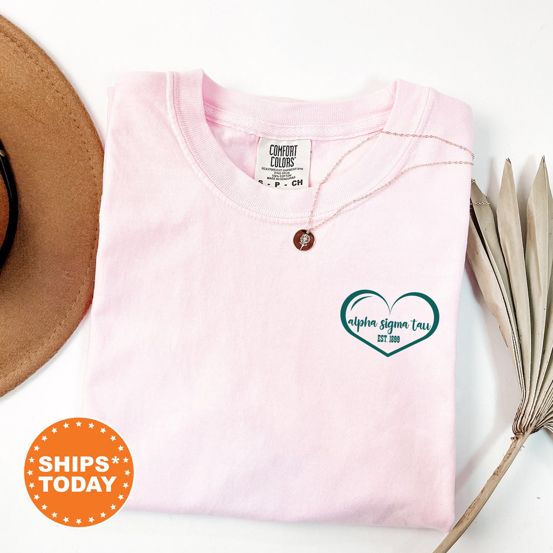 a pink shirt with a heart on it next to a hat and a pair of