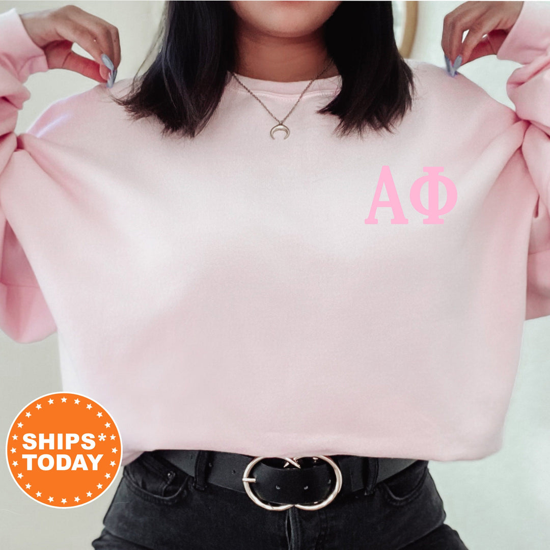 a woman wearing a pink sweatshirt with a phi phi symbol on it